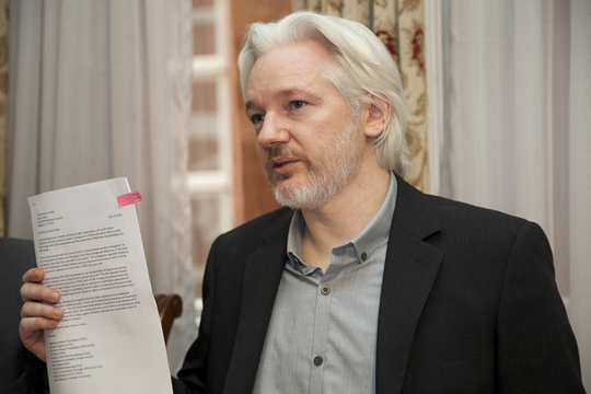 Julian Assange houdt een papier vast.