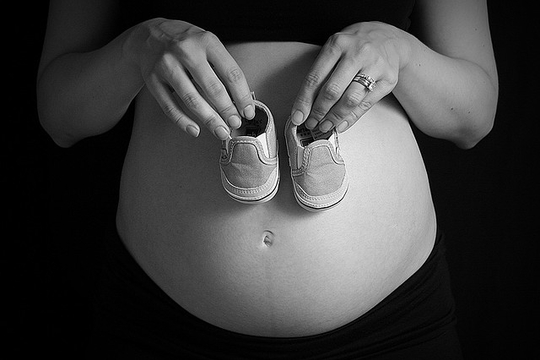 Une femme enceinte tenant des chaussons pour bébé (Photo: Trevor Bair/ Juillet 2009/ Flickr-CC)