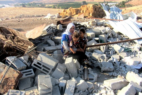Een Palestijns gezin bij de ruïne van hun door de Israëlische overheid vernielde woning in de Jordaanvallei in augustus 2015 (Foto: ‘Aref Daraghmeh, B’Tselem)
