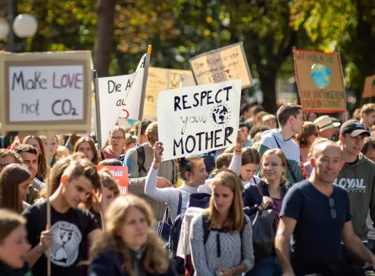 Groep mensen met kartonnen bordjes op een klimaatbetoging. 