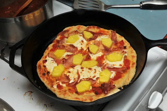 Pizza met ananas in een pan. 