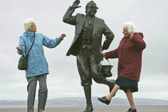 Twee oudere vrouwen doen de bewegingen van een standbeeld na.