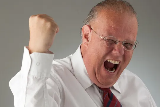 Een man in pak juicht en steekt zijn vuist in de lucht. 