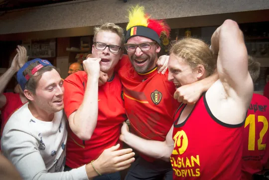 Vier uitbundige fans van de Rode Duivels vieren op café. 