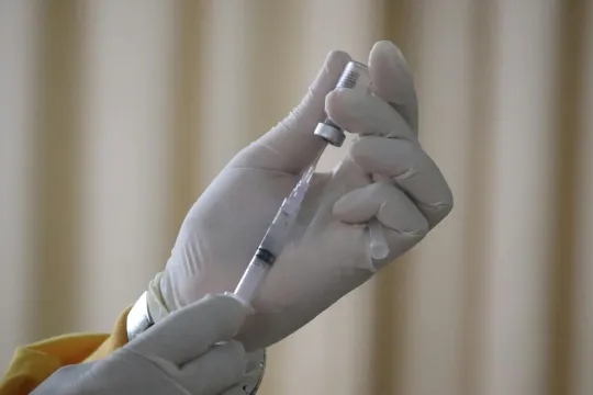 Close-up van de handen van een verplegend persoon die een vaccin voorbereidt. 