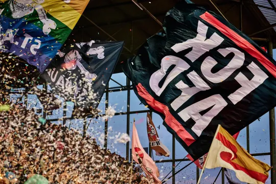 Voor, tijdens en nog heel lang na de match zwaaien supporters met regenboog-, piraten- en andere vlaggen – waarvan een met de niet mis te verstane boodschap “FCK AFD” op.