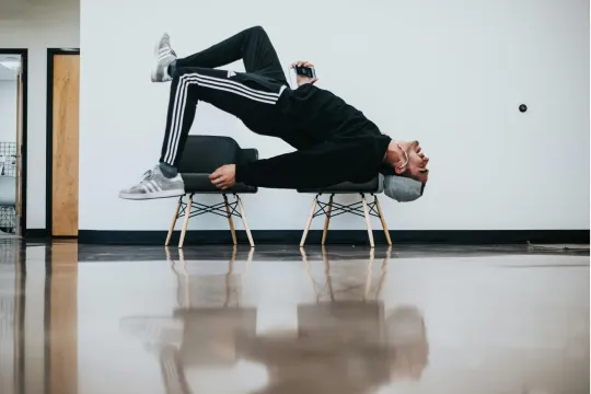 Een persoon tilt zijn eigen gewicht, liggend op twee stoelen. 