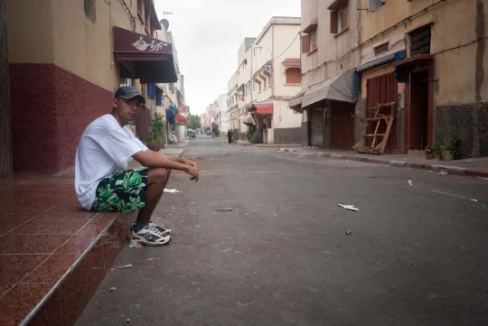 Issam assis sur le bord d'un trottoir, Derb Marrakech. (Photo: Benoît Theunissen, 2012)