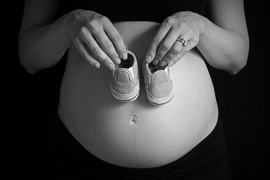 Une femme enceinte tenant des chaussons pour bébé (Photo: Trevor Bair/ Juillet 2009/ Flickr-CC)