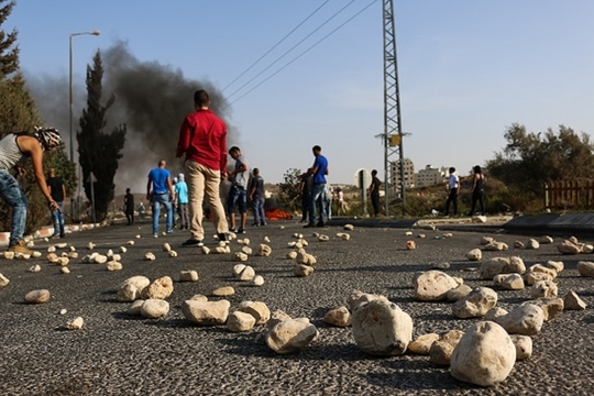 De weg vlak bij de Israelische kolonie Beit El ligt bezaaid met stenen na de clashes met het Israelische leger de afgelopen dagen. (Foto Muhanned Darabee)