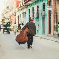 We kijken op de rug van een man die met een contrabas door de straten van Cuba wandelt.