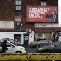 Een reclameposter met een afbeelding van Jim Ratcliffe, mede-eigenaar van Manchester United en CEO van chemieconcern INEOS, met de slogan "Als je Manchester United kunt kopen, kun je meer belasting betalen".