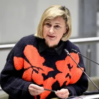 De Vlaamse minister van Binnenlands Bestuur en Integratie, Hilde Crevits, in een felgekleurde bloementrui, staat voor het spreekgestoelte tijdens een plenaire vergadering van het Vlaams Parlement in Brussel. 