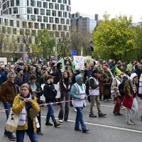 Klimaatbetogers van verschillende organisaties lopen door een hoofdstraat in Brussel.