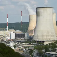 Drie grote dampende kerncentrales in een industrieel landschap. 